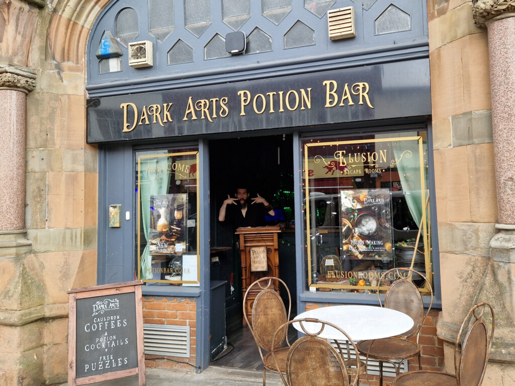 An Image of the entrance to The Dark Arts Potion Bar, featuring Senior Warlock Drew throwing a pose for the camera