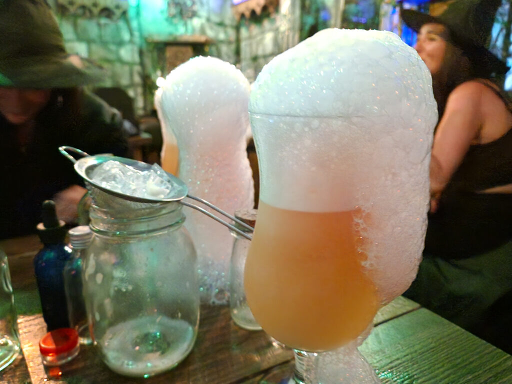 Bubbling orange-coloured cocktails with foamy topping spilling out of each glass