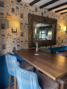 An image showing The Cross Keys bar area, with wooden tables and chairs and a gold mirror.